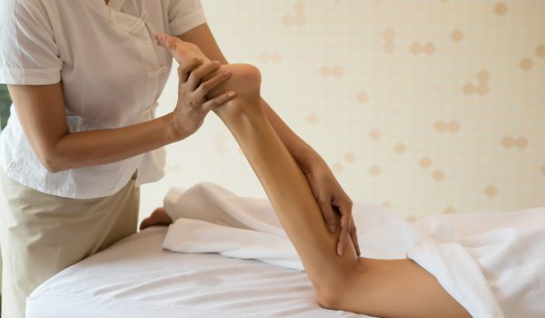 Close Up of massage therapist massaging female leg at spa salon.